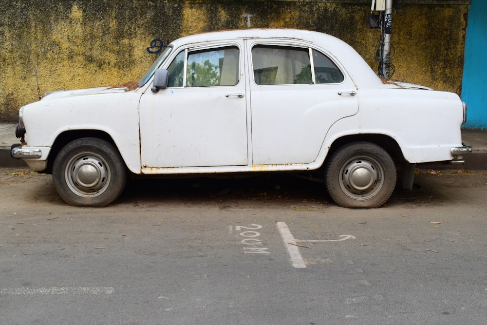 an old white car parked on the side of the road