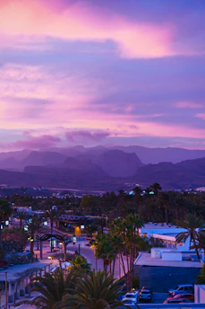 A vibrant sunset over Monterrey's city skyline with mountains in the background.