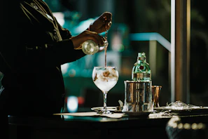 a person pouring a drink into a glass
