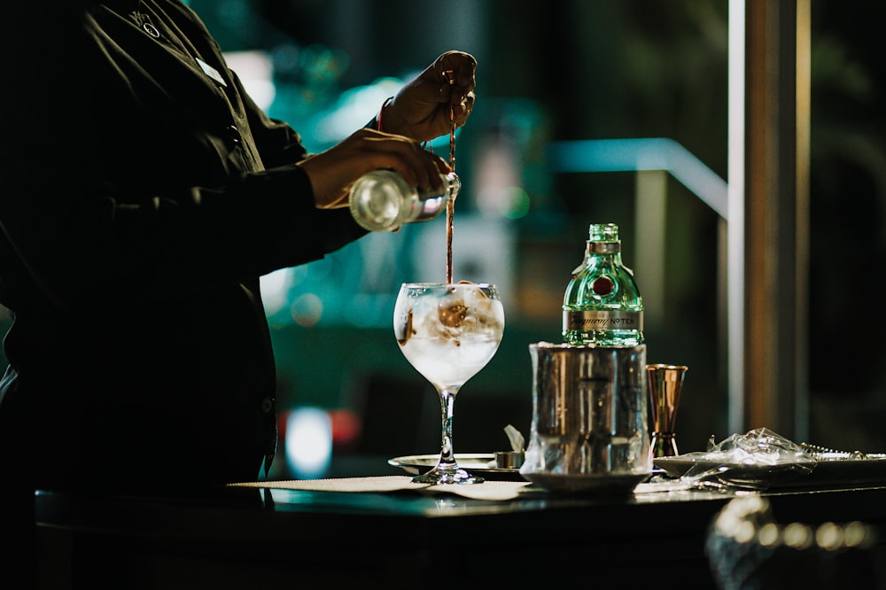 a person pouring a drink into a glass