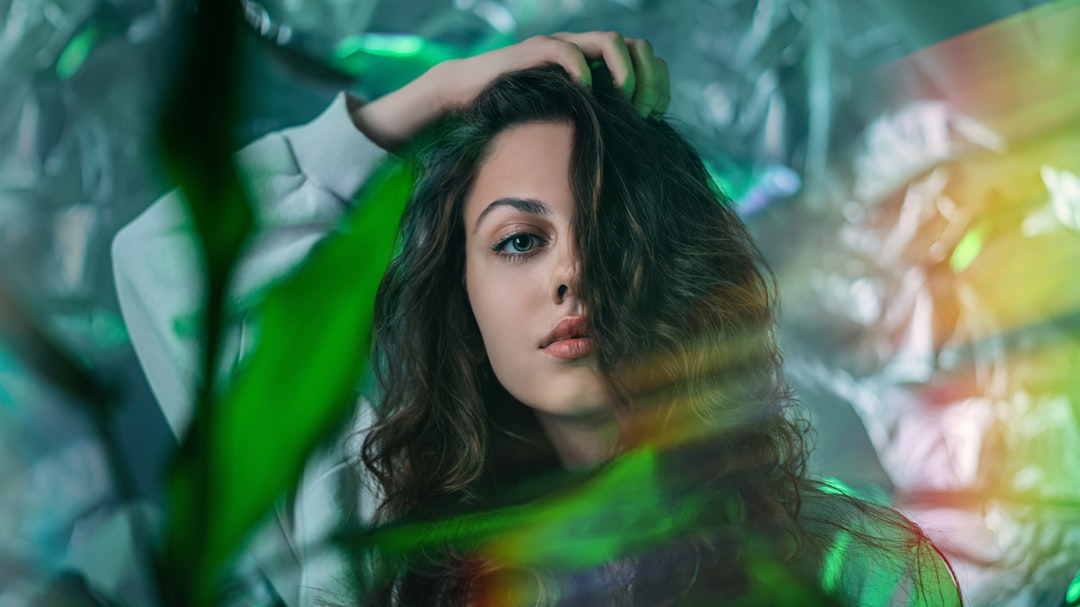 woman in green scarf standing under green leaves