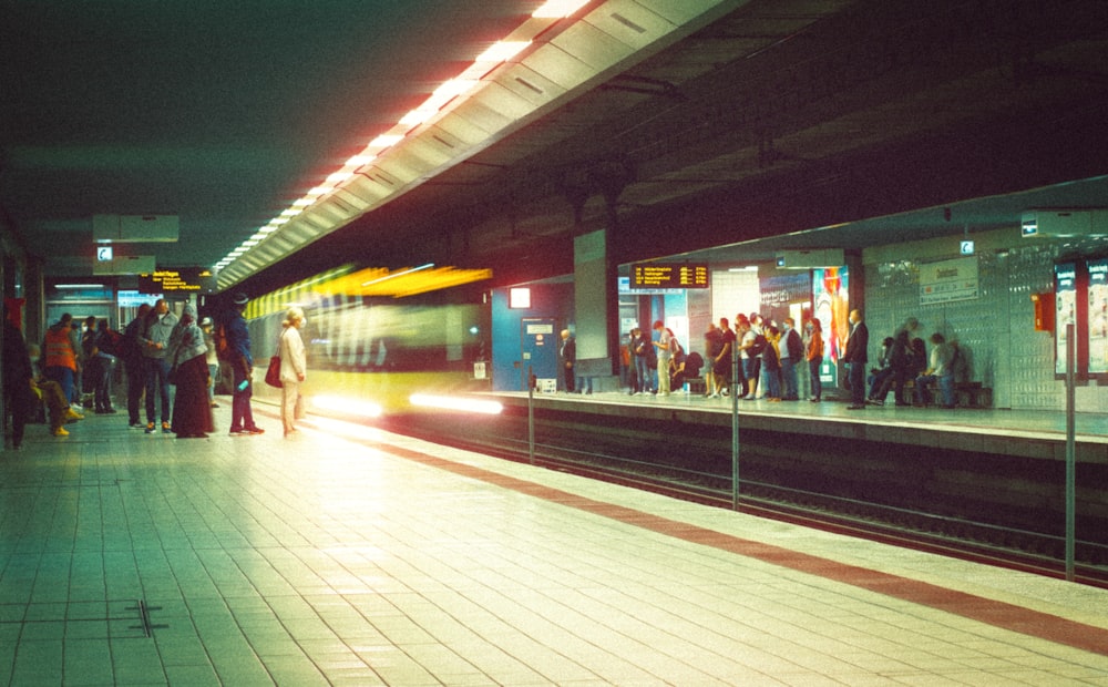 a group of people waiting for a train at a train station