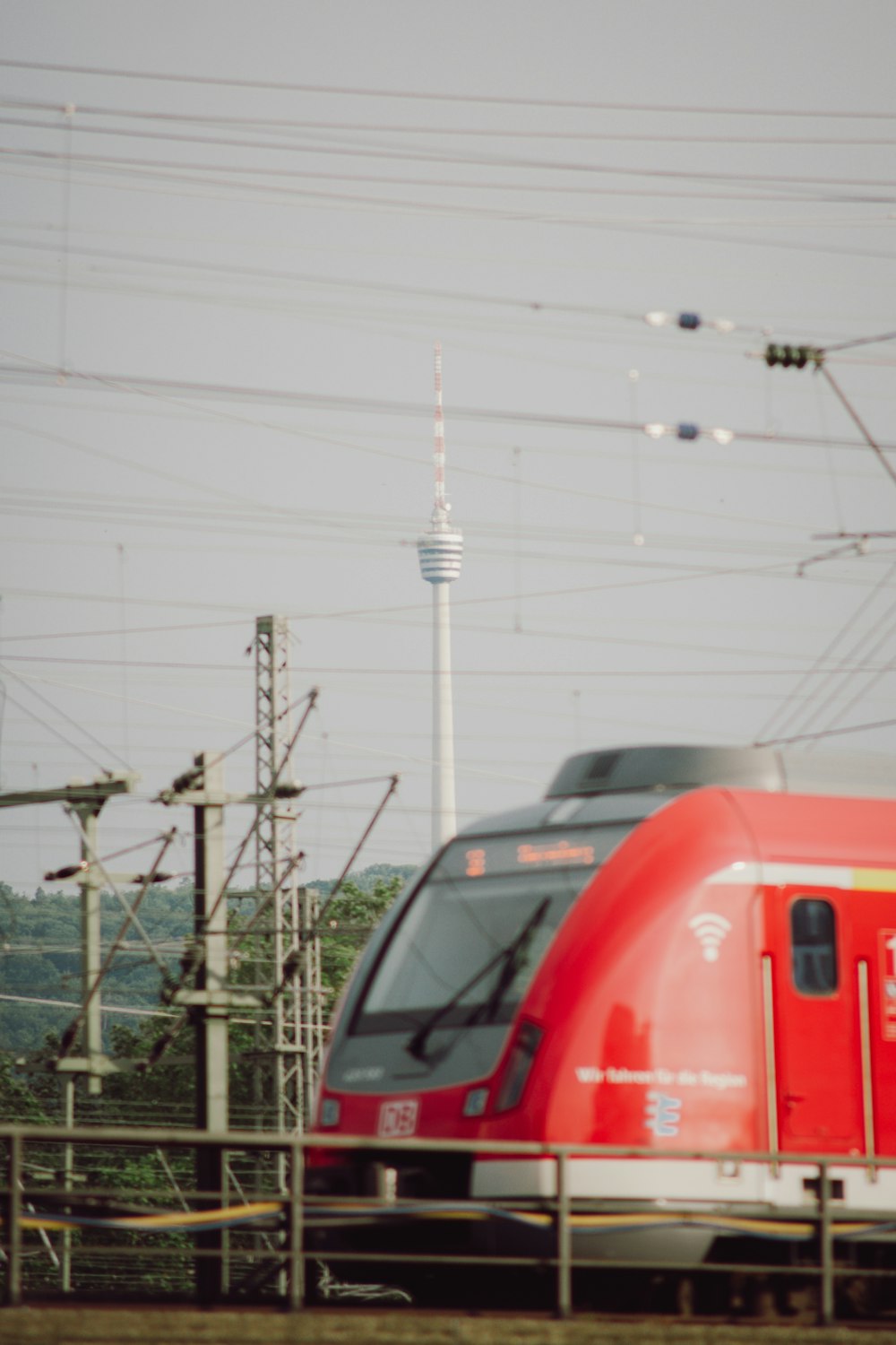 a red train traveling down train tracks next to a forest