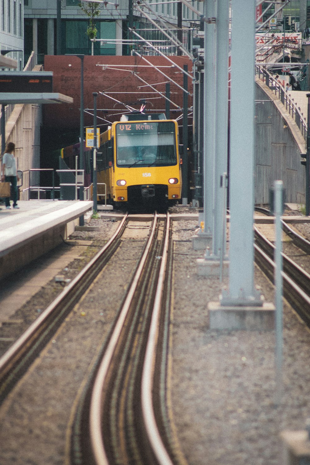 a yellow train traveling down train tracks next to a tall building