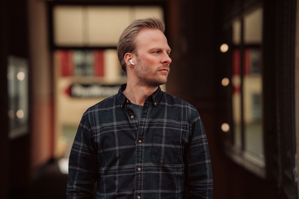 a man standing in front of a building with ear buds in his ears