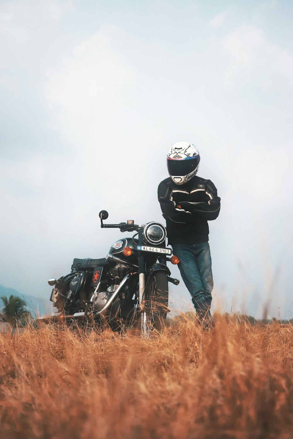 a man standing next to a motorcycle in a field