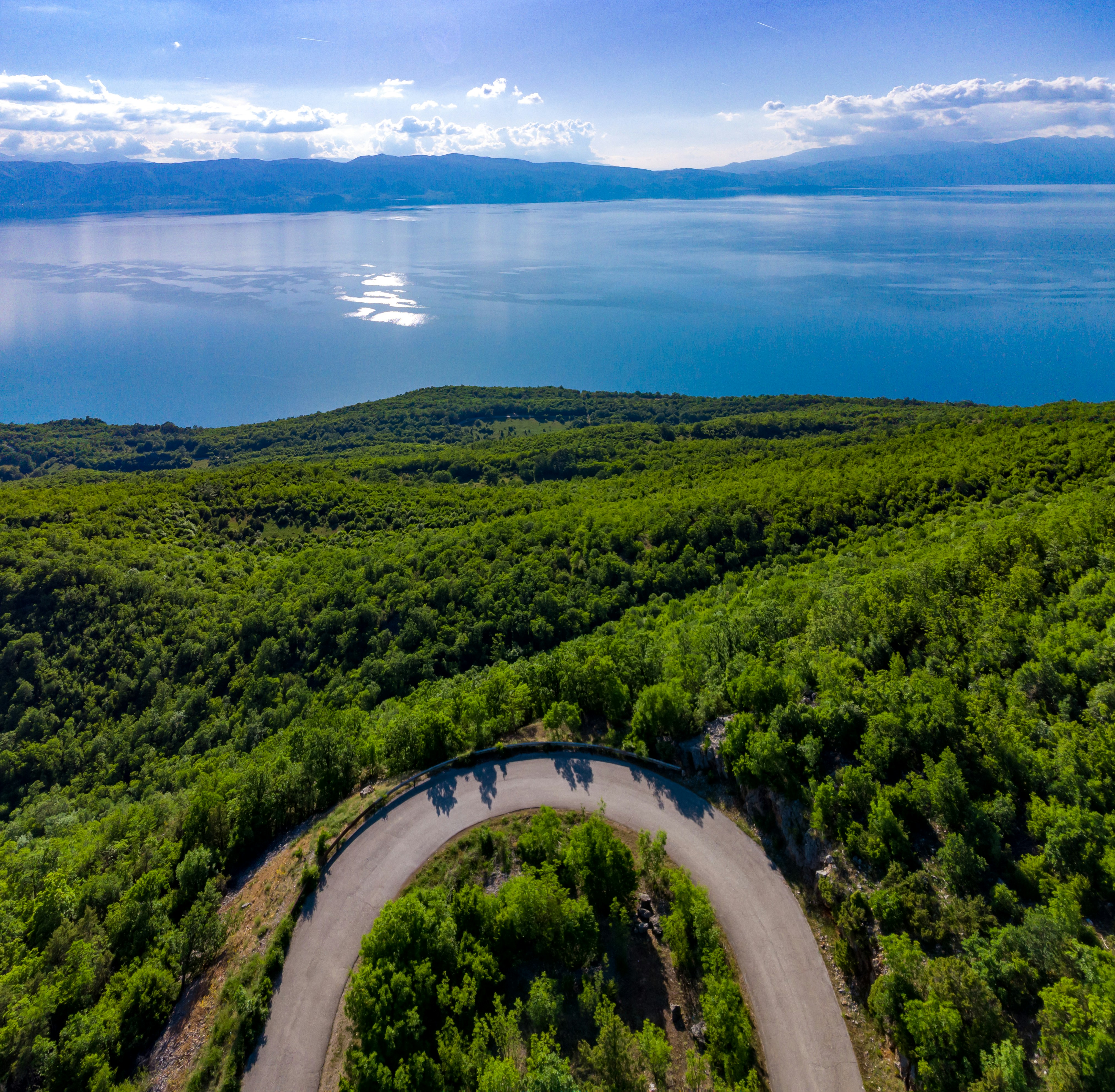 an aerial view of a winding road in the middle of a forest