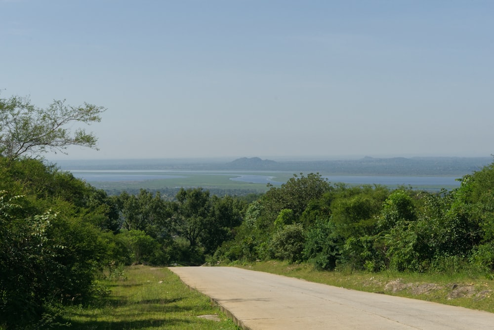 an empty road with a view of a lake in the distance