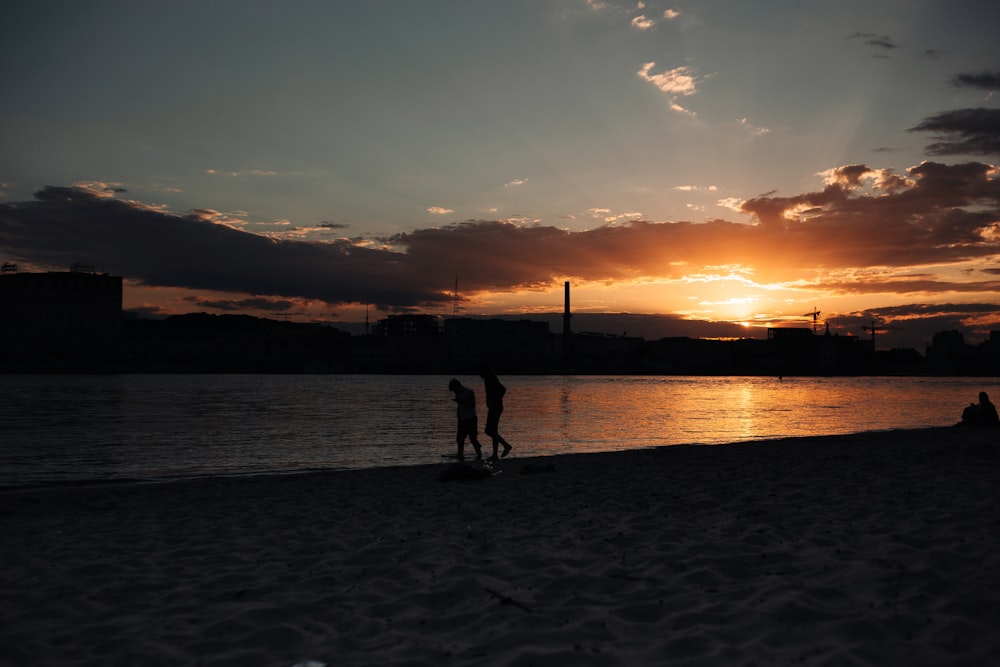 a couple of people standing on top of a sandy beach