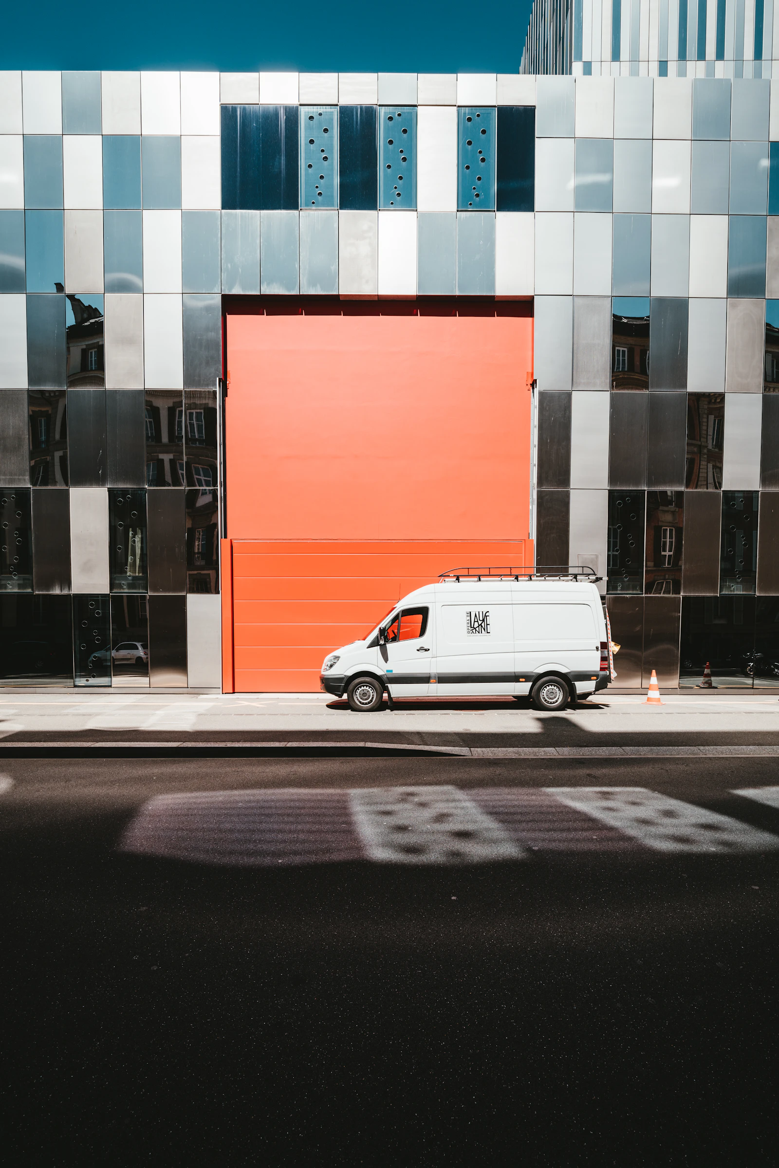 A delivery van parked at the curb in front of a building