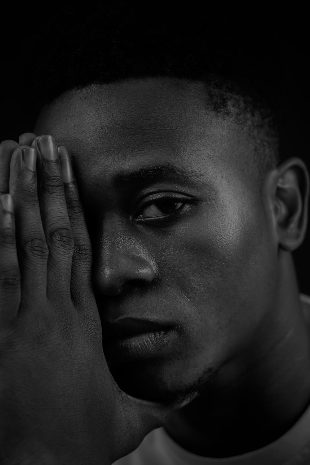 a black and white photo of a man holding his hands to his face