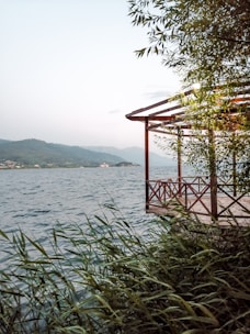 A serene lakeside property with a wooden deck and trees surrounding it.