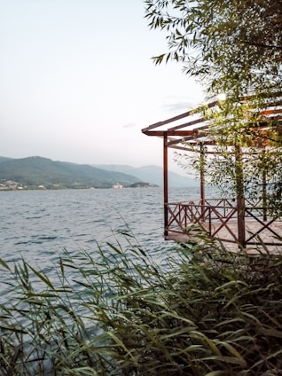 A serene lakeside property with a wooden deck and trees surrounding it.