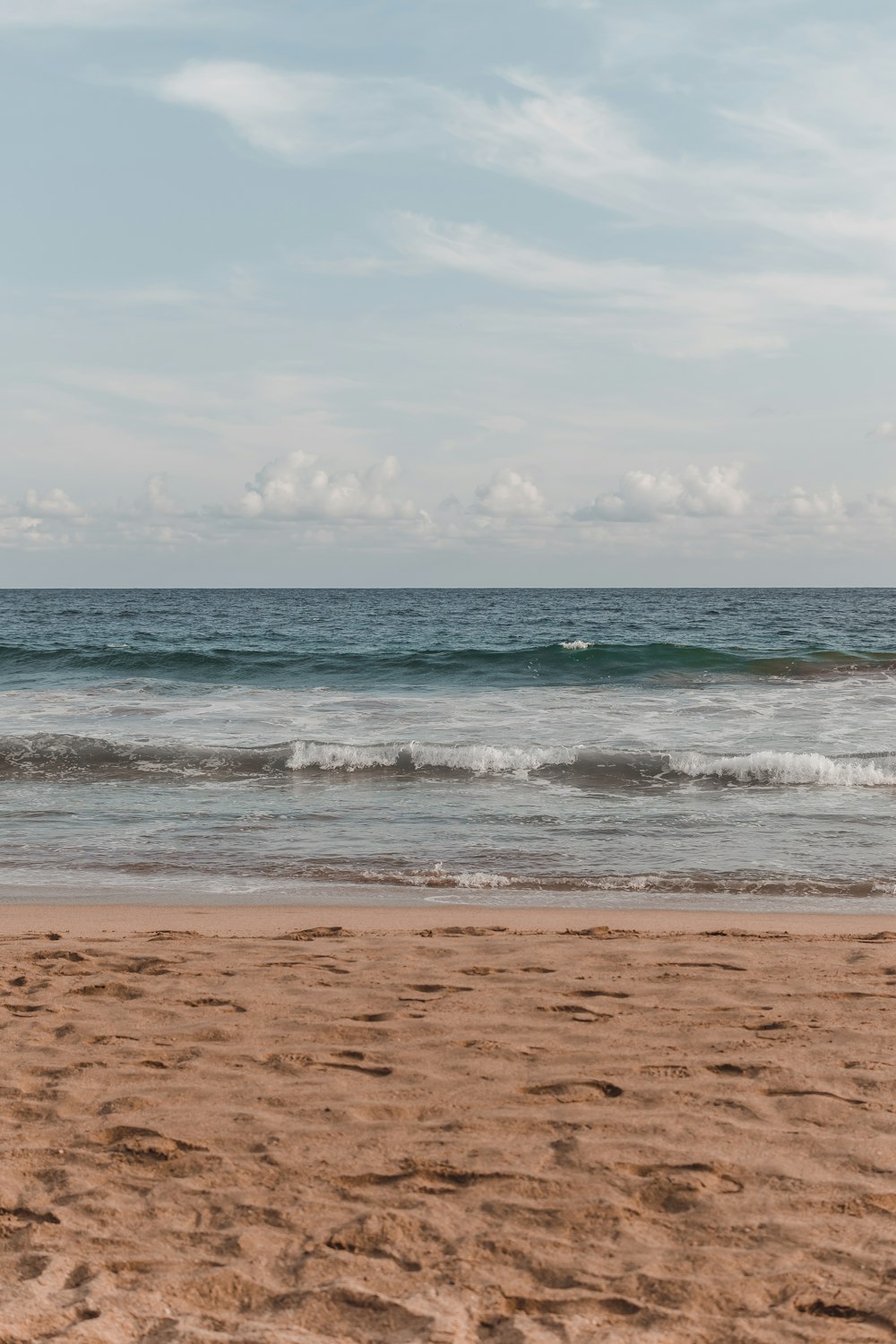 a person walking on the beach with a surfboard