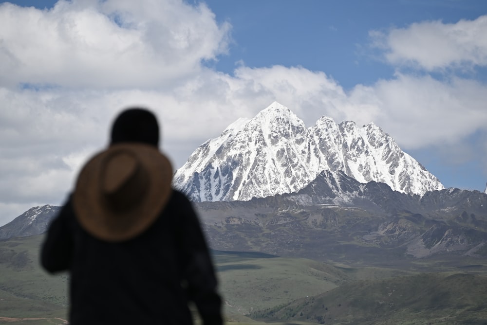 Un hombre parado frente a una montaña cubierta de nieve