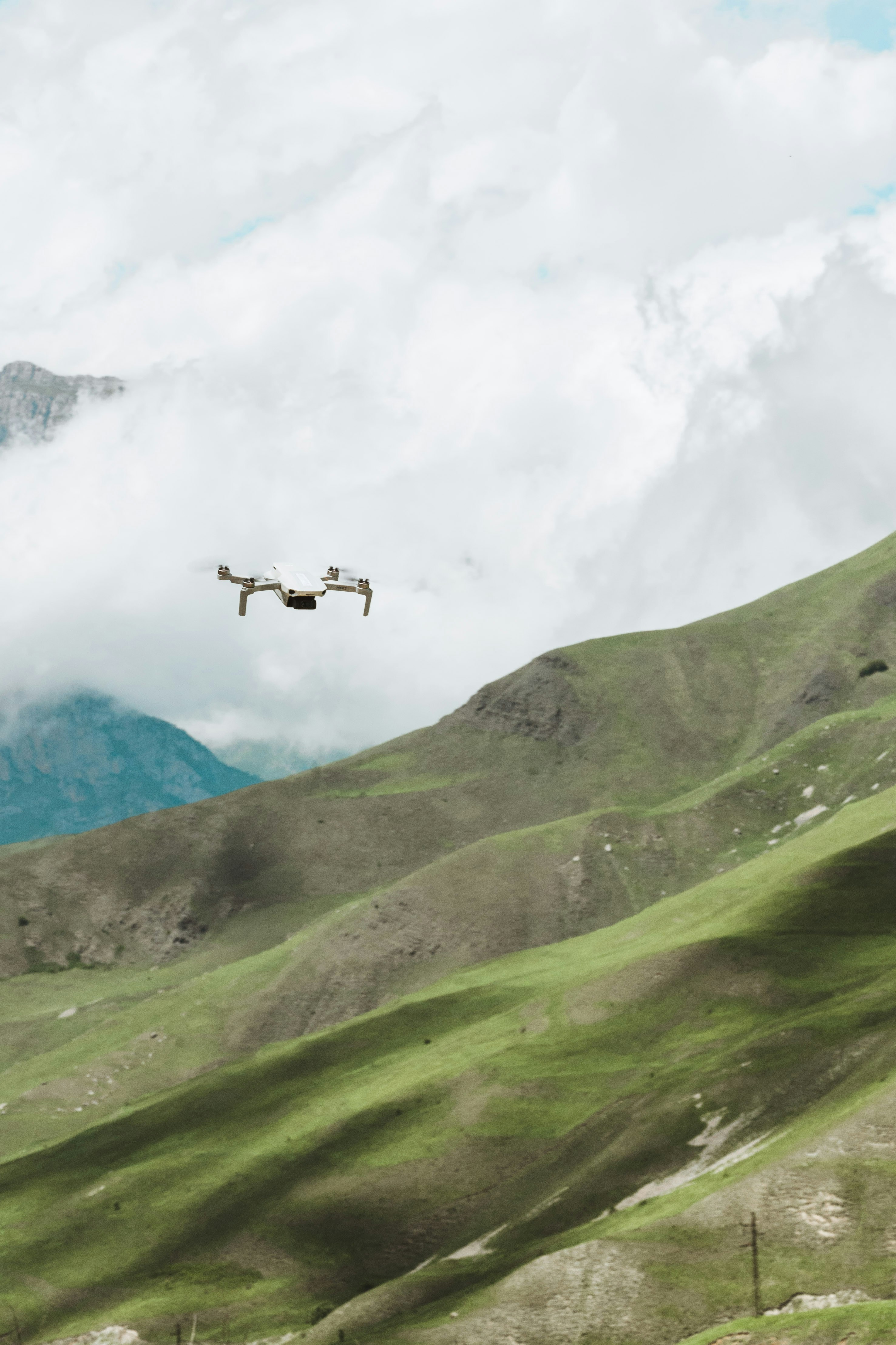 a small plane flying over a lush green hillside