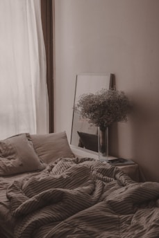 a bed with a blanket and a vase with flowers