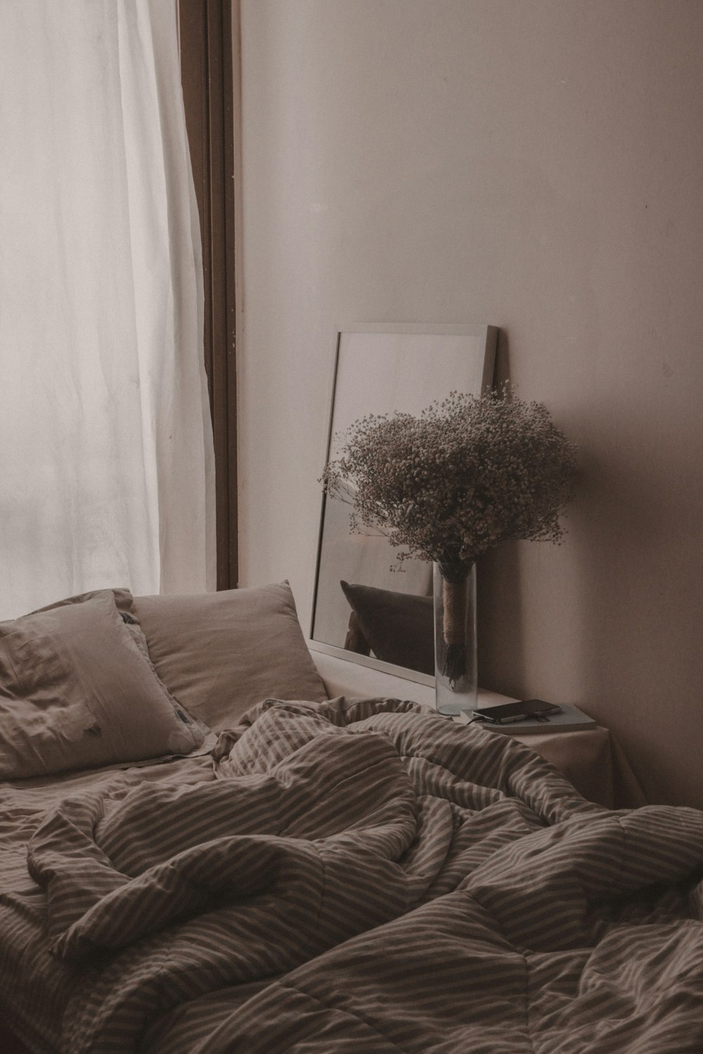 a bed with a blanket and a vase with flowers