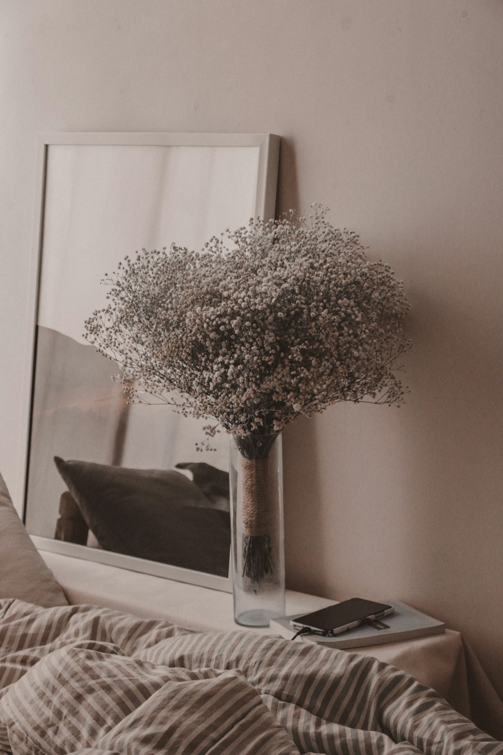 a vase filled with baby's breath sitting on top of a bed