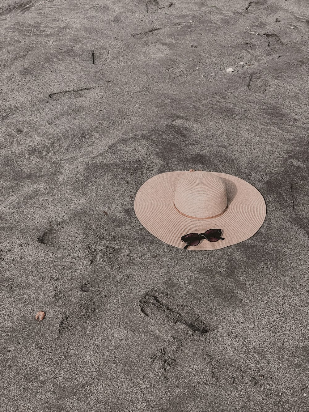a hat and sunglasses are sitting in the sand