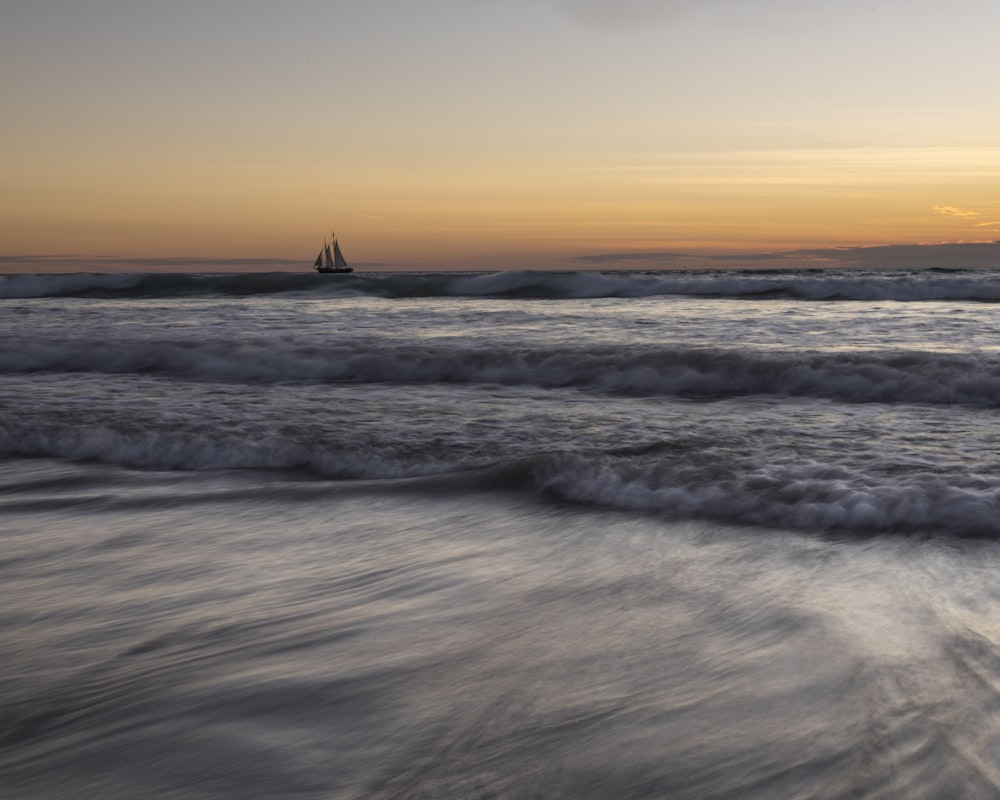 a sailboat in the ocean at sunset