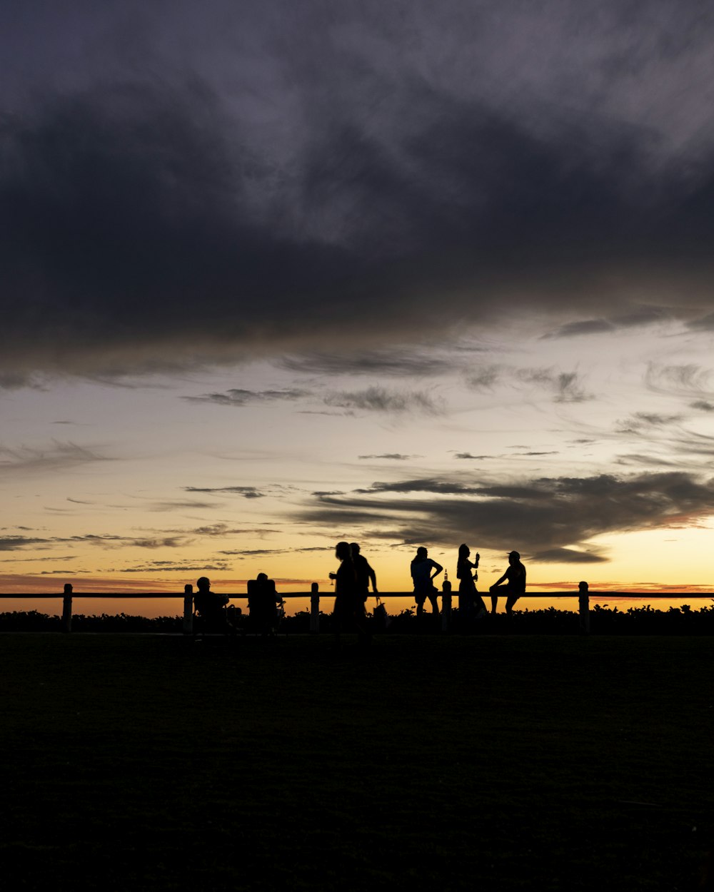 a group of people walking across a field under a cloudy sky