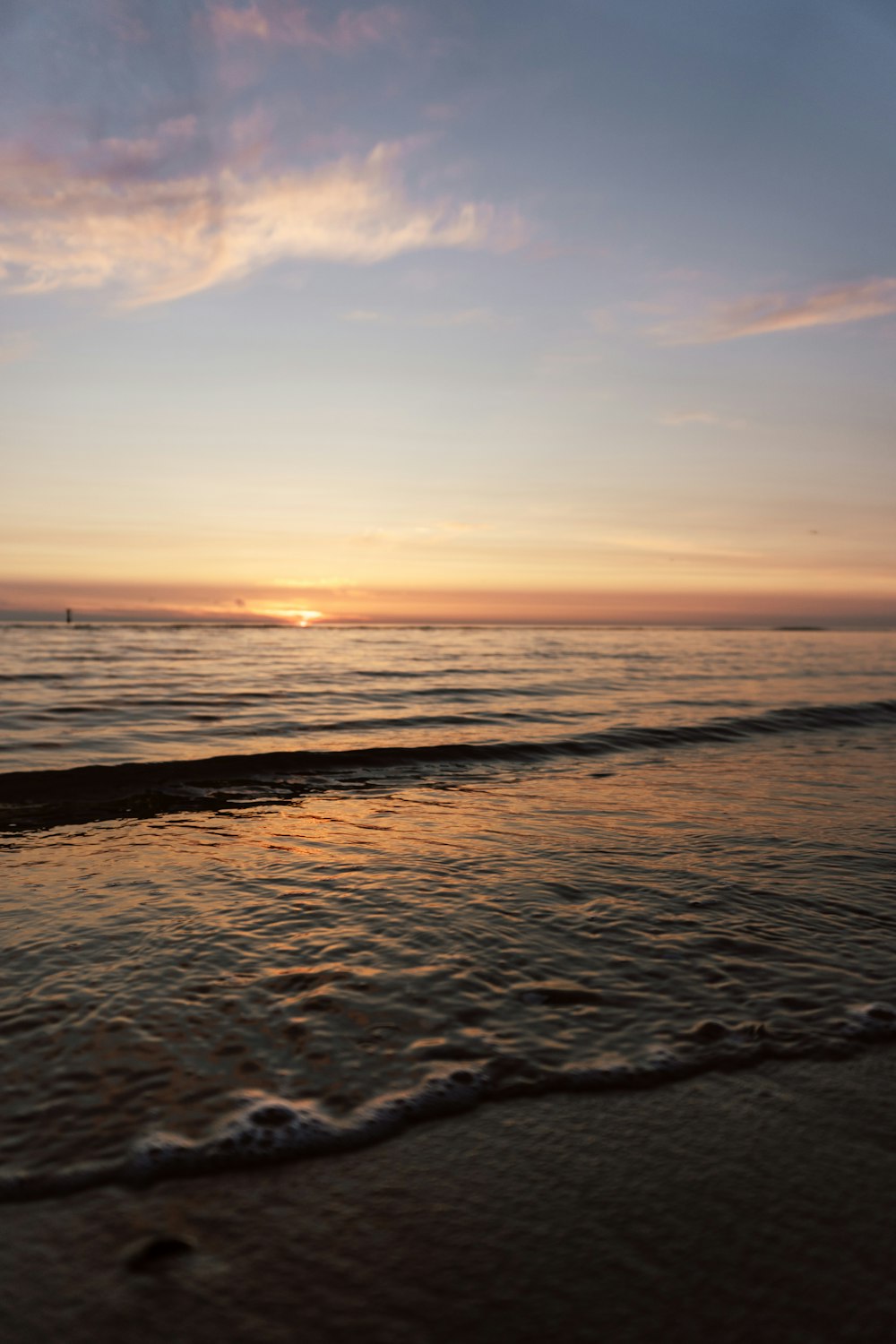 the sun is setting over the water at the beach