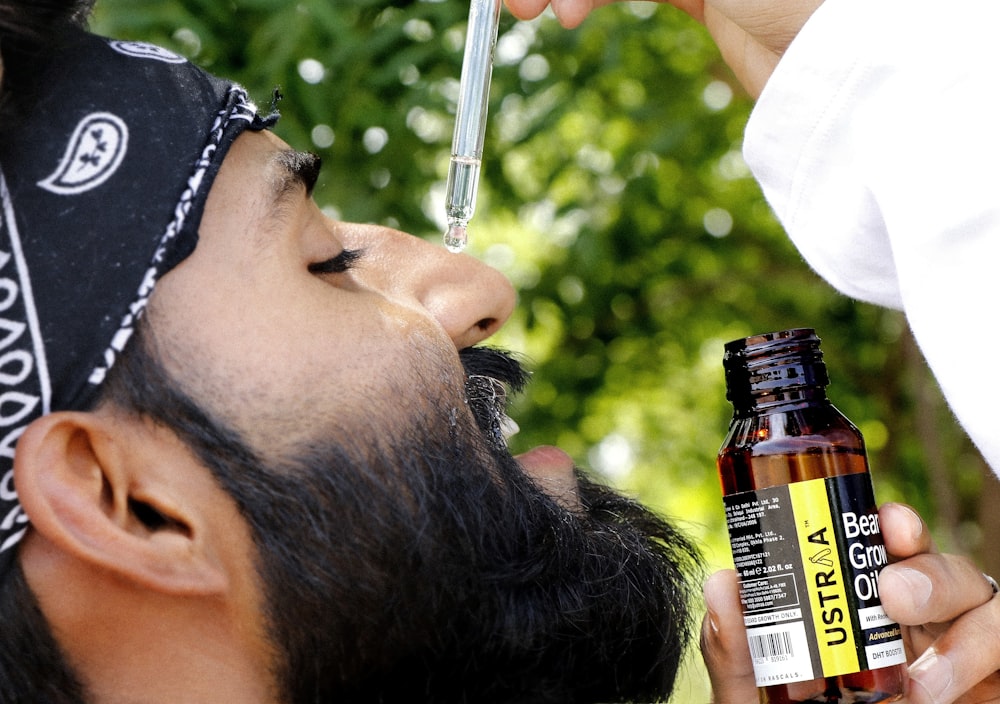 a man with a bandanna on his head is holding a bottle of beer