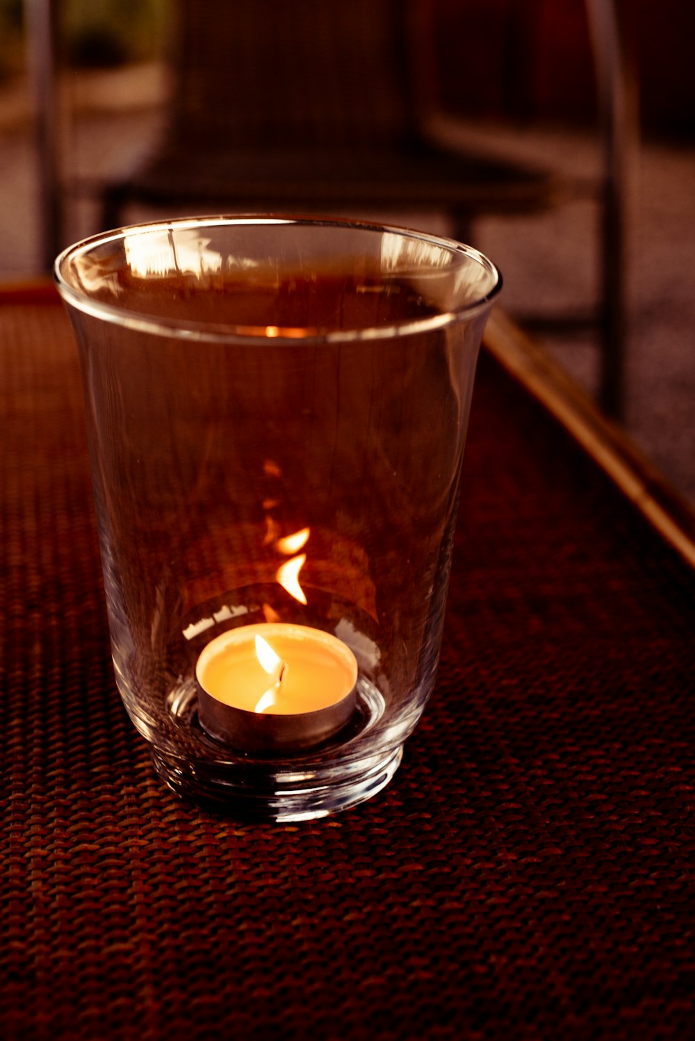 a lit candle in a glass on a table