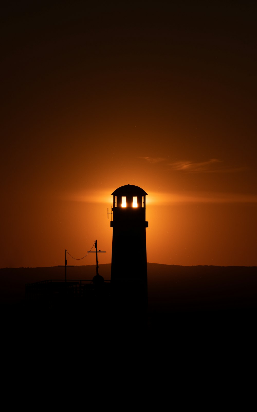 the sun is setting behind a light house