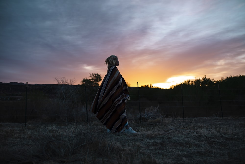 a person wrapped in a blanket standing in a field