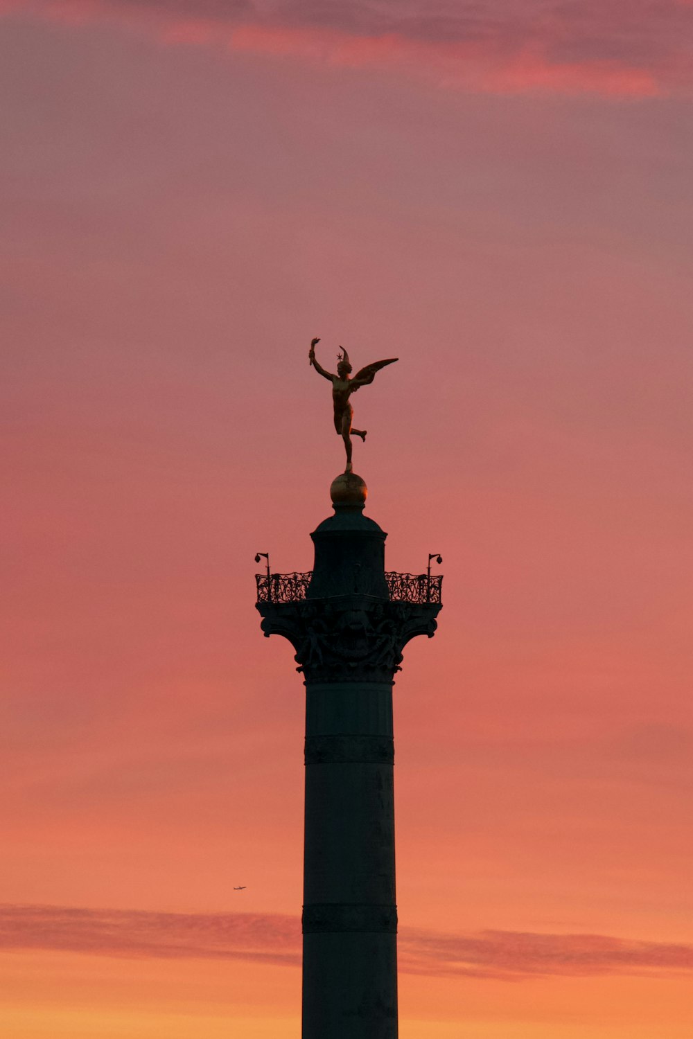 uma estátua no topo de uma torre com um pássaro em cima dela