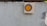 A light-colored concrete block with small speckles and visible texture is in the foreground. A small wooden square with a painted circle, featuring a gray outer ring and an orange center, is mounted on the right side of the block.