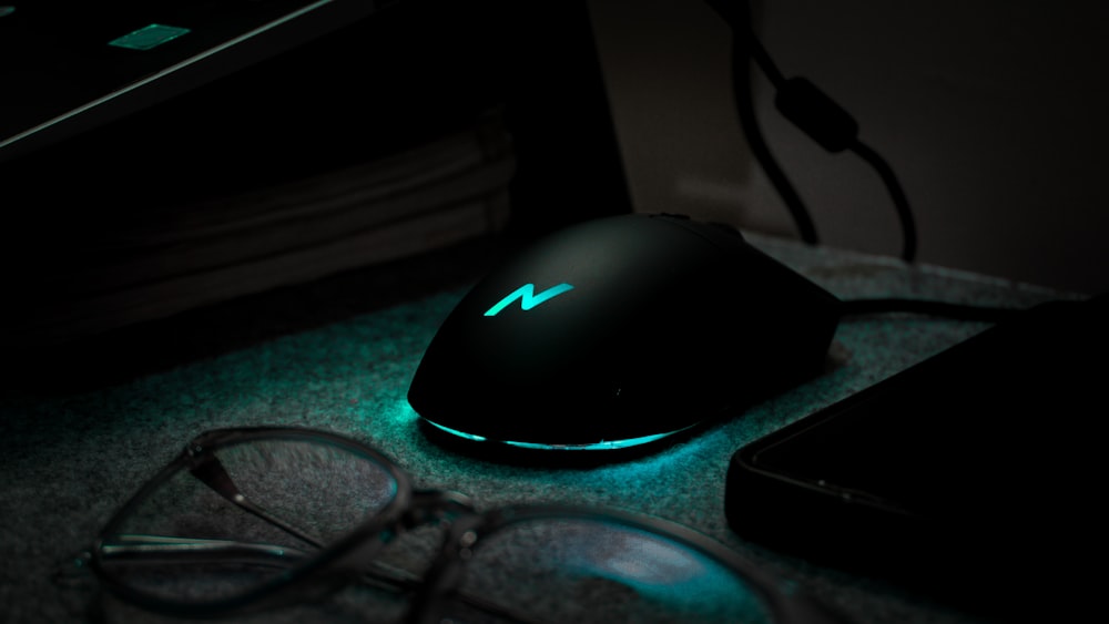 a computer mouse sitting on top of a desk next to a pair of glasses