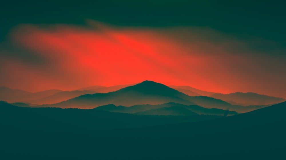 Un cielo rojo y verde sobre una cadena montañosa