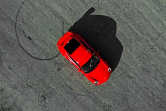 an overhead view of a red car in a parking lot