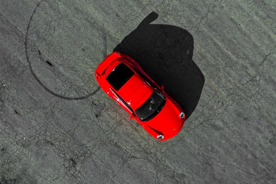 an overhead view of a red car in a parking lot