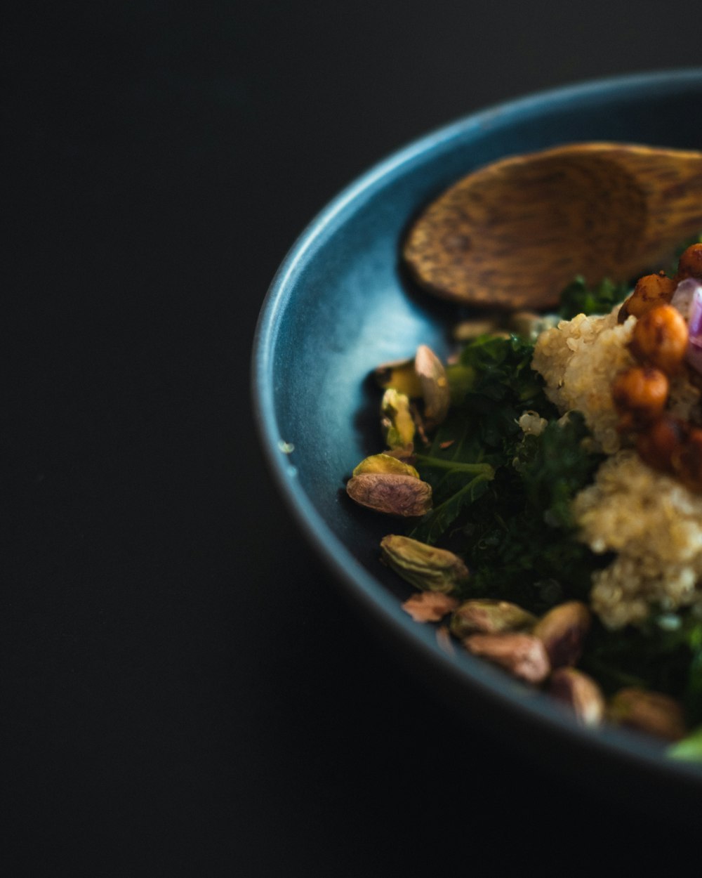 a blue bowl filled with food and a wooden spoon