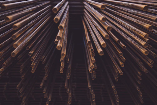 Bundles of copper mulberry rods stacked tightly in a factory setting.