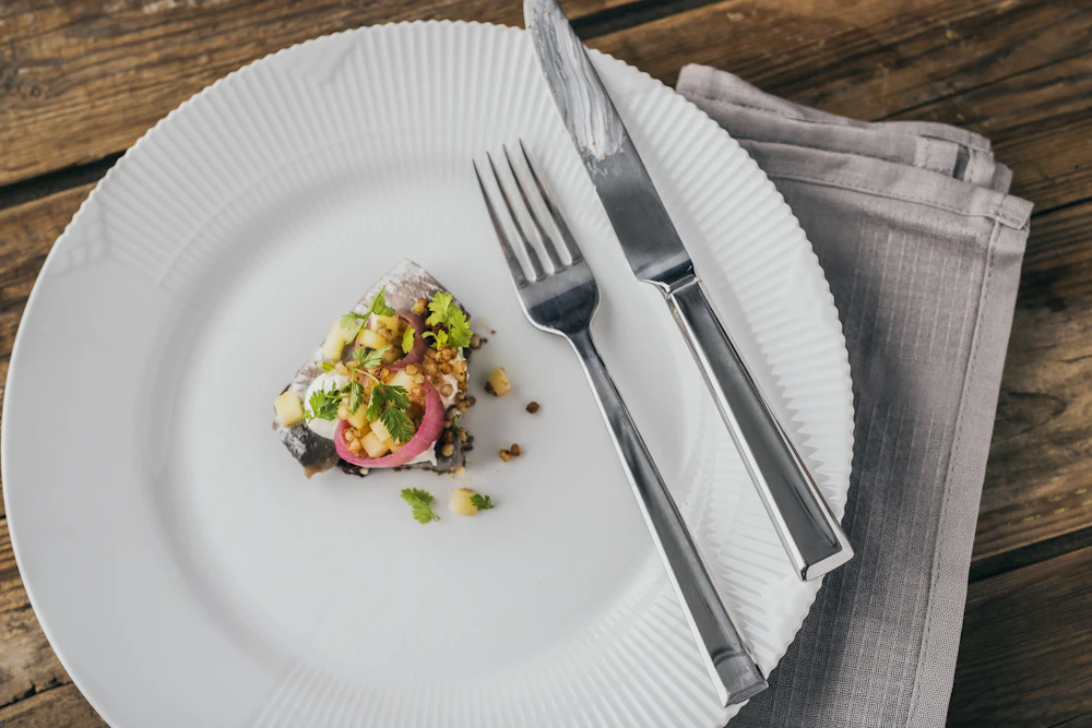 Fischgericht mit roten Zwiebeln und Kräutern auf einem weissen Teller