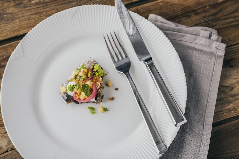 Un plato blanco cubierto con comida junto a un tenedor