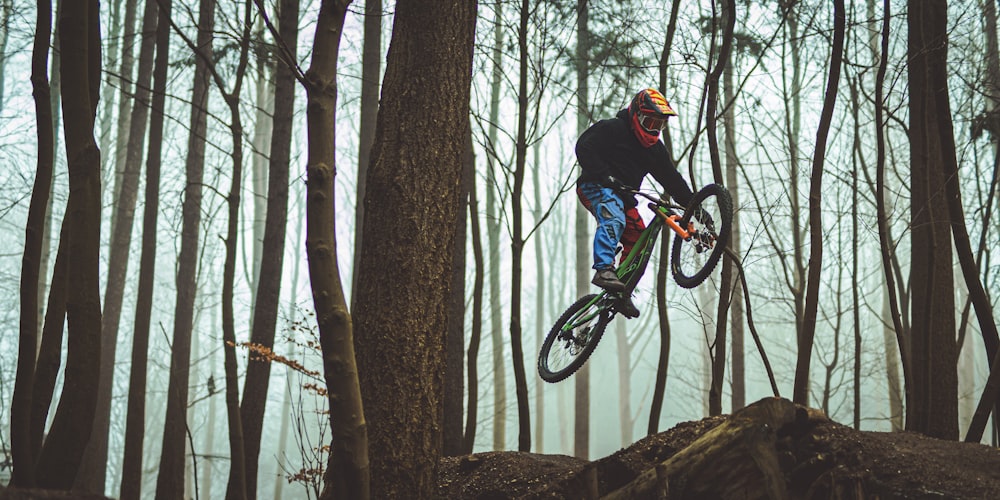 a man riding a bike through a forest filled with trees