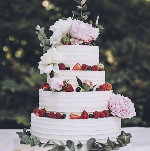 a white wedding cake with fresh strawberries and flowers