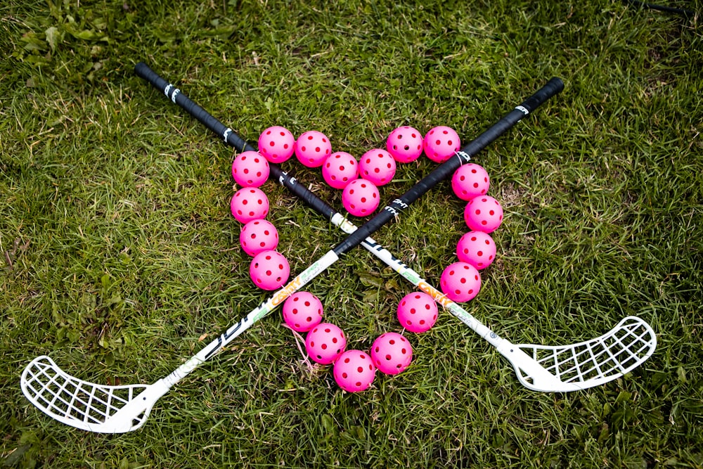 a heart made out of pink balls and lacrosse sticks