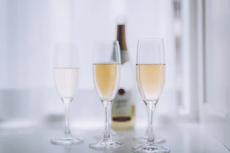 three glasses of champagne sitting next to a bottle of wine