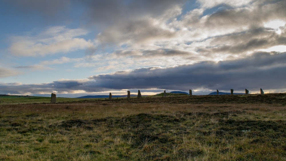 a grassy field with a row of stonehenge in the distance