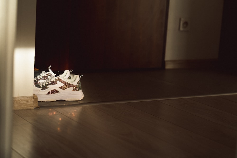 a pair of white sneakers sitting on top of a wooden floor