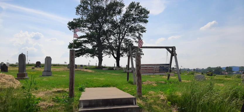 A serene memorial site bathed in warm sunset light with flags gently waving in the breeze.