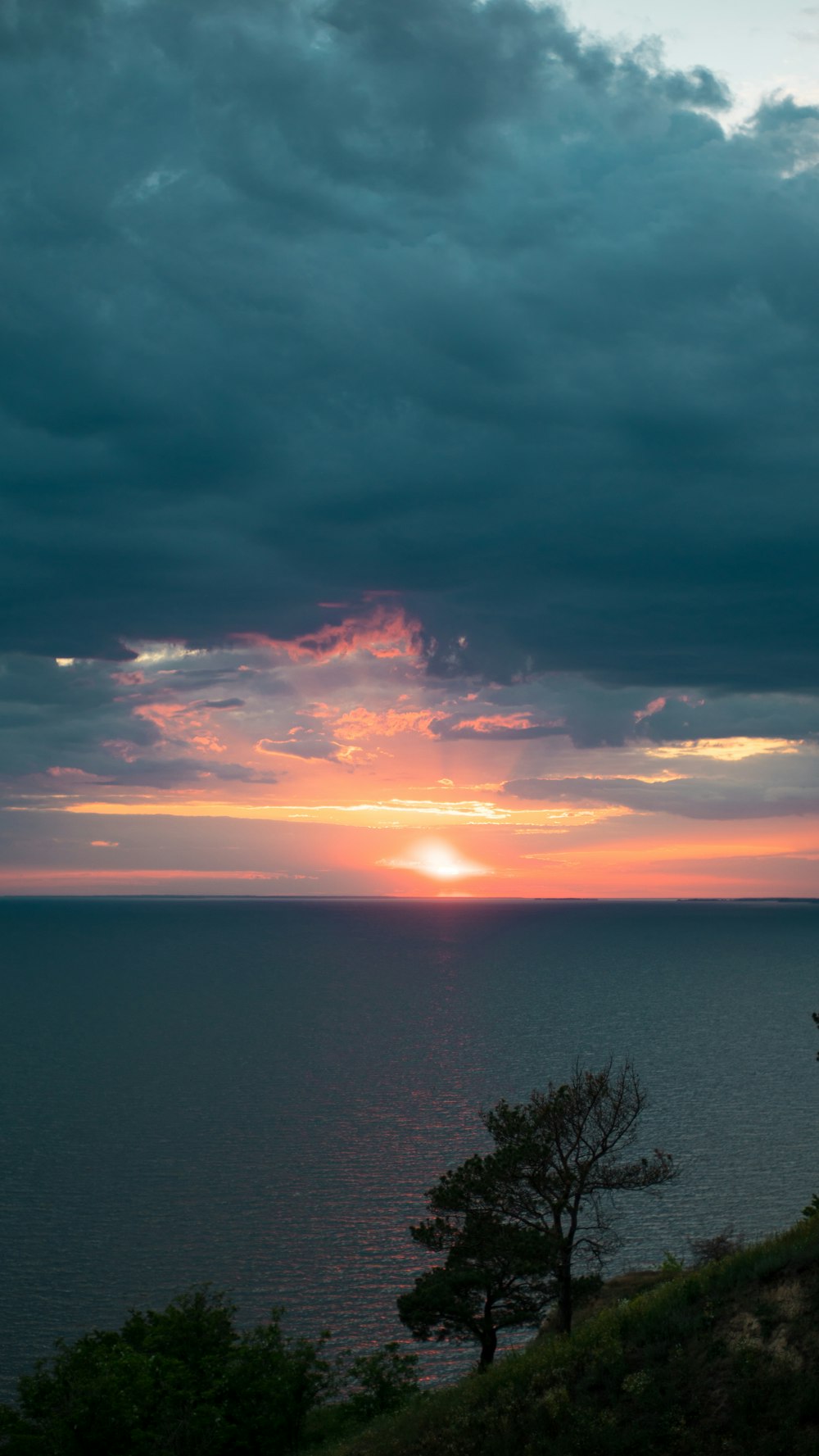 the sun is setting over the ocean on a cloudy day