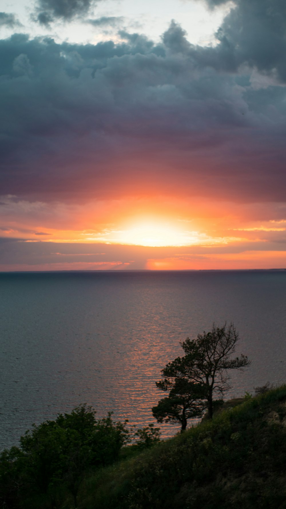 the sun is setting over the ocean on a cloudy day